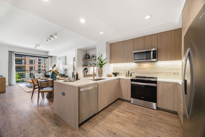 Kitchen with a refrigerator, oven, microwave and dishwasher leading towards the dining and living room area