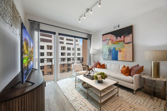 Living room with a TV, sofa sitting and a standing balcony