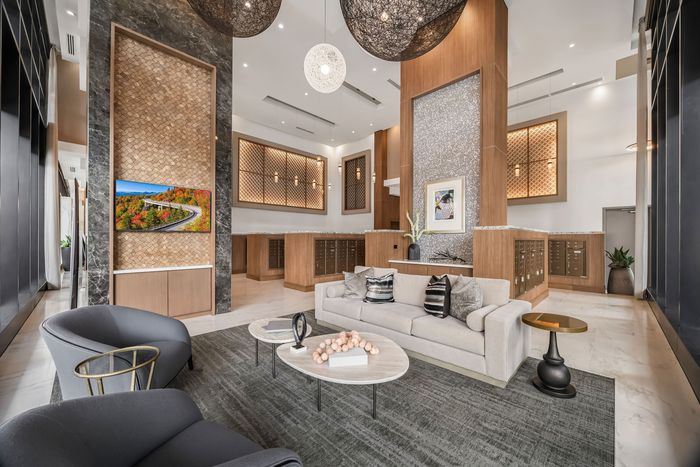Sitting area inside the mail room with couch, two chairs a coffee table and tv