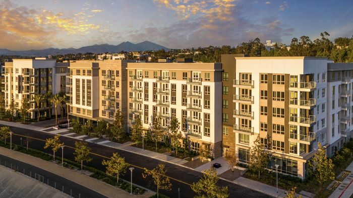 Exterior view of 6 story apartment building with mountains in the distant background