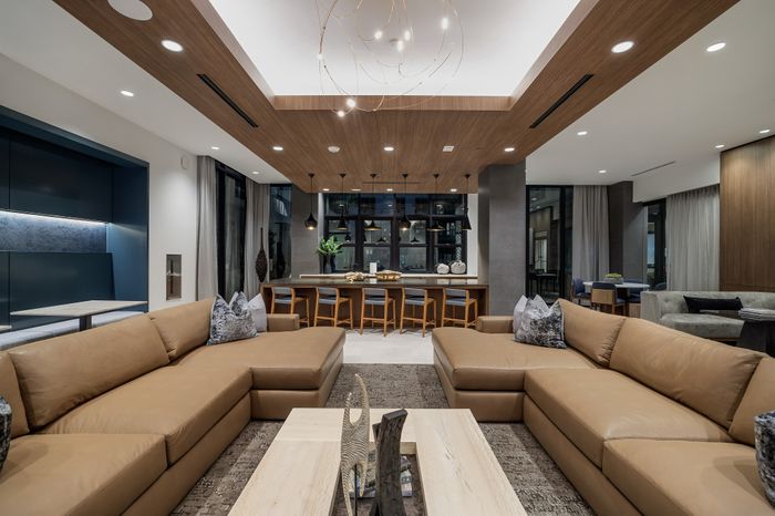 amenity club room in apartment with two sectional sofas in front of kitchen area with counter seats and pendant lighting