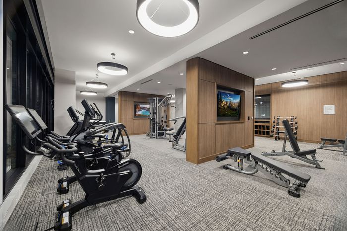 fitness center with row of carddio machines and weight machines beyond
