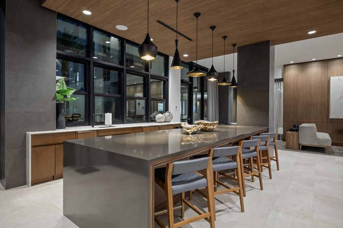 entertaining kitchen with island with 5 counter stools and adjacent counter with sink and sliding windows behind