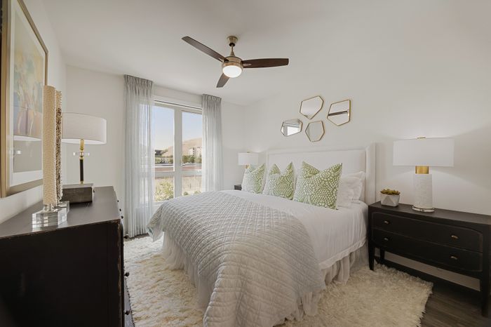 bedroom in apartment with king size bed, oversized windows, and ceiling fan light fixture