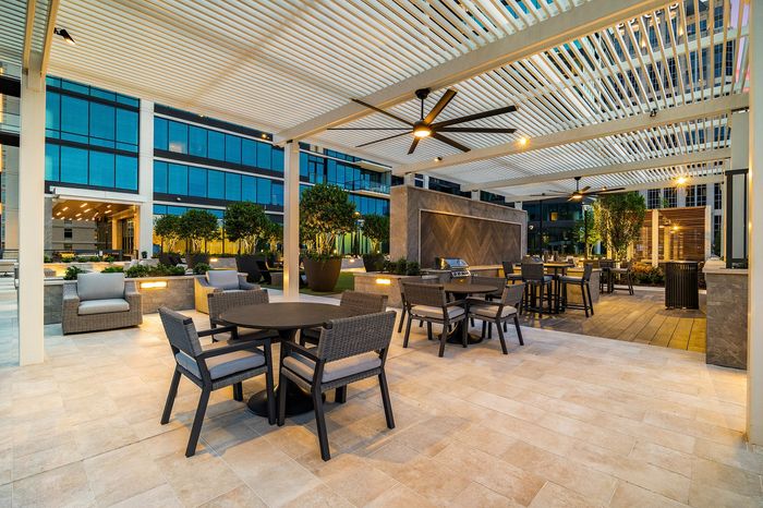 outdoor dining and grilling area with slatted arbor above