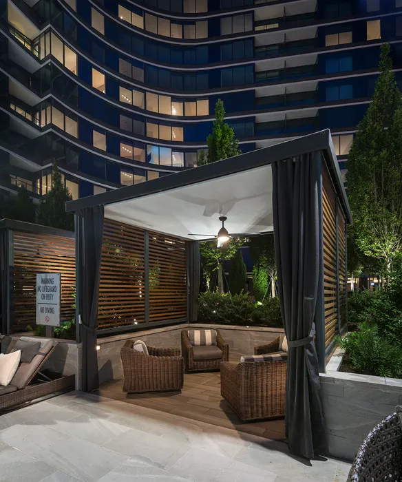 outdoor lounge area with wicker furniture and ambient lighting, surrounded by lush greenery.