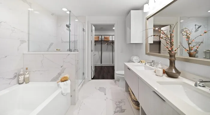 Luxurious bathroom showcasing elegant marble tiles, modern double sink vanity, and a spacious bathtub with glass shower enclosure.