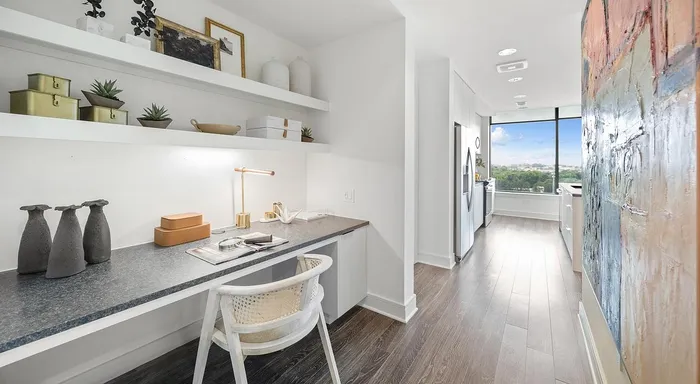 Contemporary home office with chic decor, leading to a modern kitchen and scenic window view.