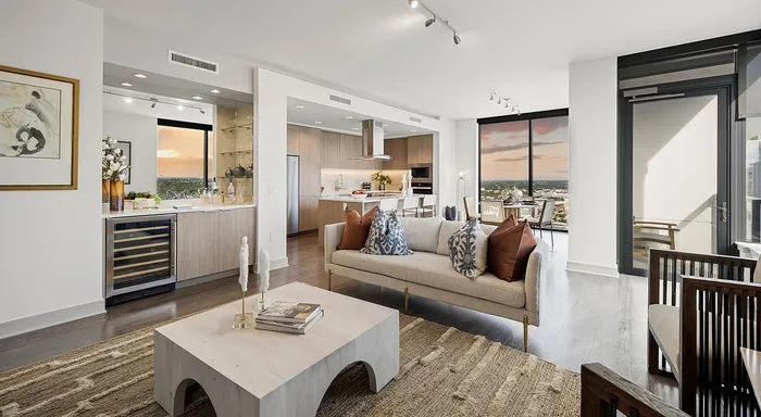 Luxurious open-plan living space with modern kitchen, stylish decor, and stunning sunset views from floor-to-ceiling windows.