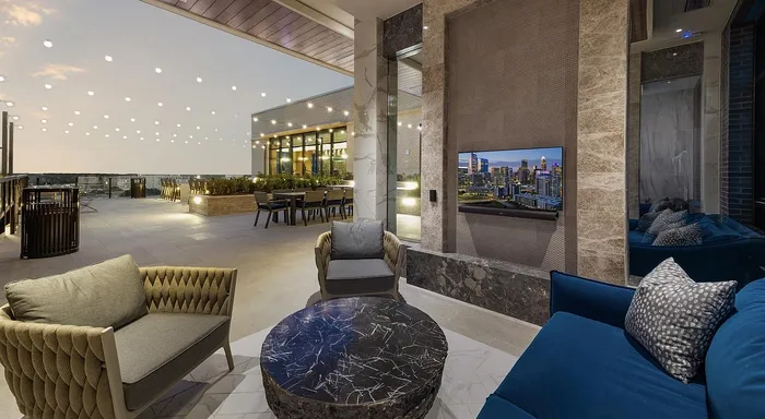 Luxurious rooftop patio with elegant seating, artistic round table, and captivating city views under ambient string lights.