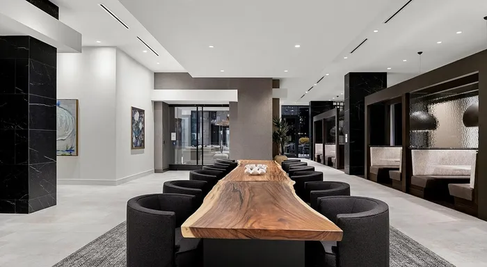 Modern, spacious lobby with a striking wooden table and elegant seating, showcasing contemporary design and ambient lighting.