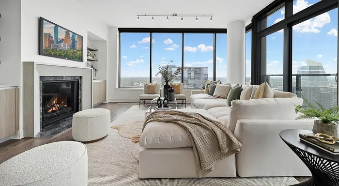 Luxurious living room with cozy fireplace, plush seating, and stunning floor-to-ceiling windows offering panoramic city views.
