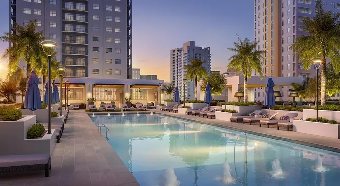 Luxurious apartment complex at sunset featuring a pristine swimming pool, elegant lounge chairs, and lush palm trees, offering a resort-style living experience.