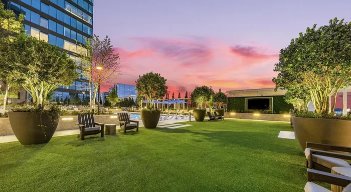 Enchanting rooftop garden with lush greenery, cozy seating, and a vibrant sunset backdrop, perfect for relaxed urban living.