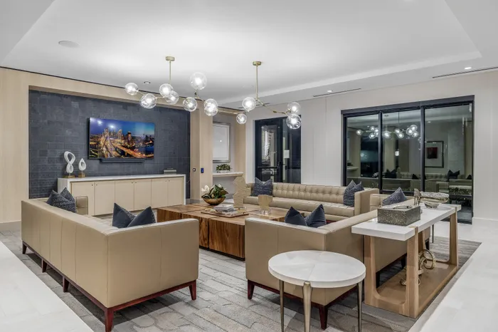 Elegant modern living room with luxurious beige leather sofas, a wooden coffee table, and contemporary lighting fixtures creating a sophisticated ambiance.