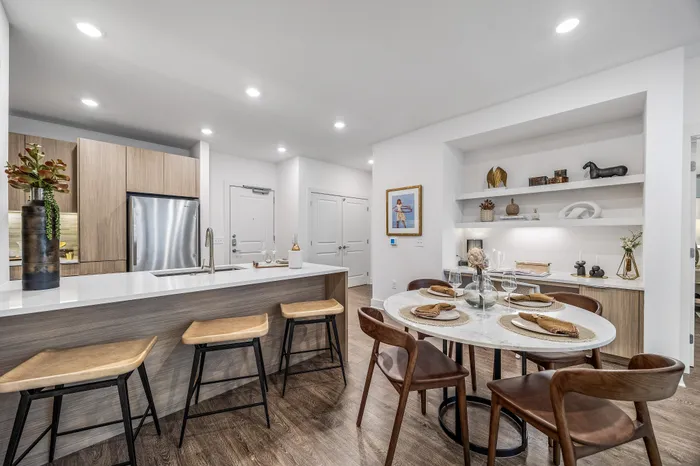 Modern kitchen and dining area with elegant wood finishes, chic lighting, and stylish decor, perfect for entertaining.