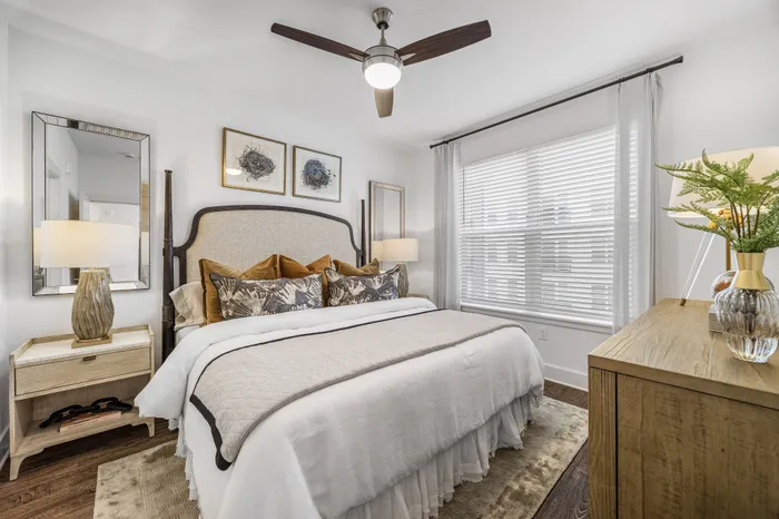 Cozy and elegant bedroom featuring a plush king-sized bed, stylish decor, and abundant natural light through large windows.