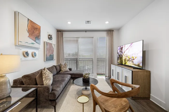 Chic modern living room with stylish decor, featuring a cozy plush sofa, artistic wall art, and a large flat-screen TV.