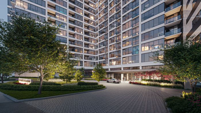 Modern high-rise apartment building with large windows, surrounded by lush landscaped gardens and a welcoming driveway entrance.