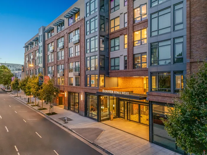 Chic urban apartment building exterior with modern design, large windows, and inviting entrance at twilight.