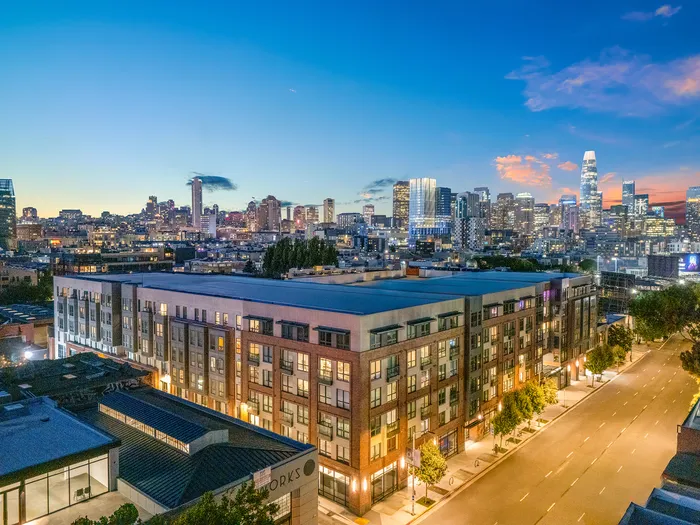 Captivating cityscape view of a modern apartment complex against a vibrant evening skyline, offering urban living at its finest.