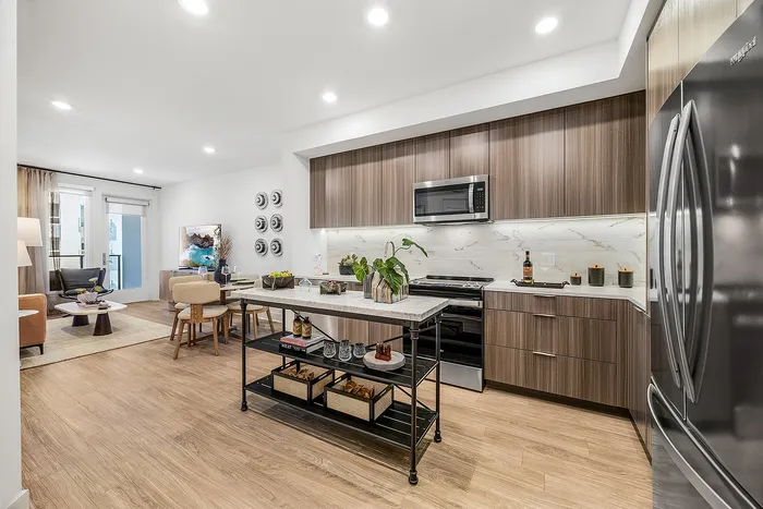Modern open-concept kitchen and living area featuring sleek wood cabinets, elegant marble backsplash, and a stylish island with ample storage.