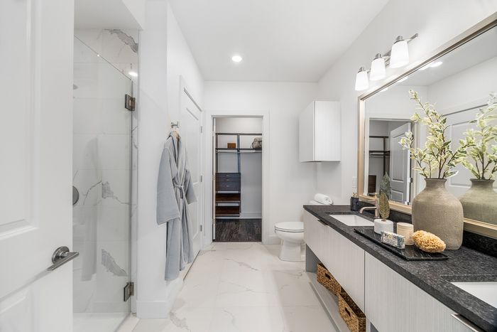 Luxurious modern bathroom with elegant marble flooring, spacious glass shower, and contemporary double vanity accented with decorative plants.
