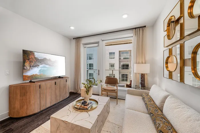 Bright and chic living room with stylish decor, featuring a cozy sofa, modern art pieces, and large windows offering natural light.