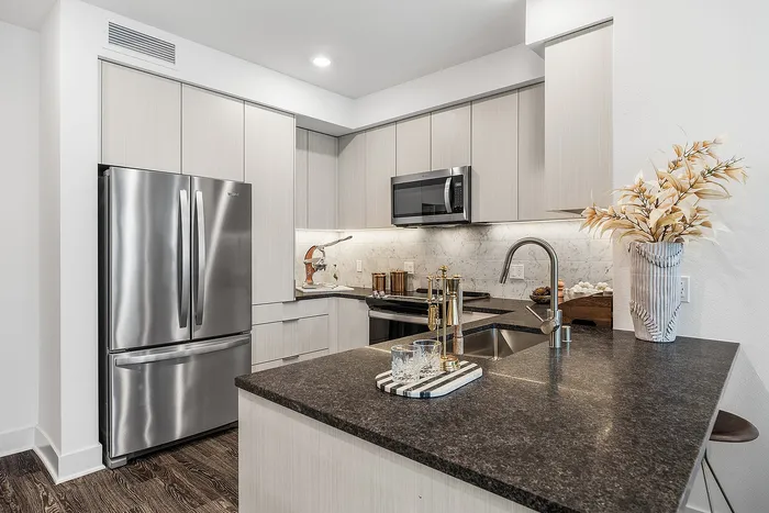 Modern kitchen with sleek stainless steel appliances, elegant marble backsplash, and stylish dark countertops.
