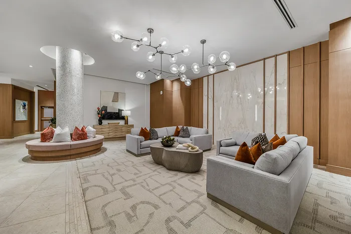 Luxurious modern living room with elegant chandeliers, plush seating, marble accents, and wooden paneling.