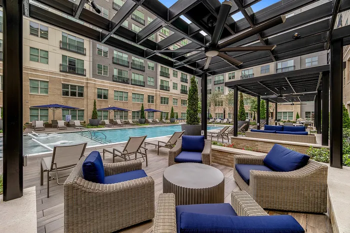 Luxurious outdoor pool area with plush wicker seating and modern pergolas, perfect for relaxation and entertainment.