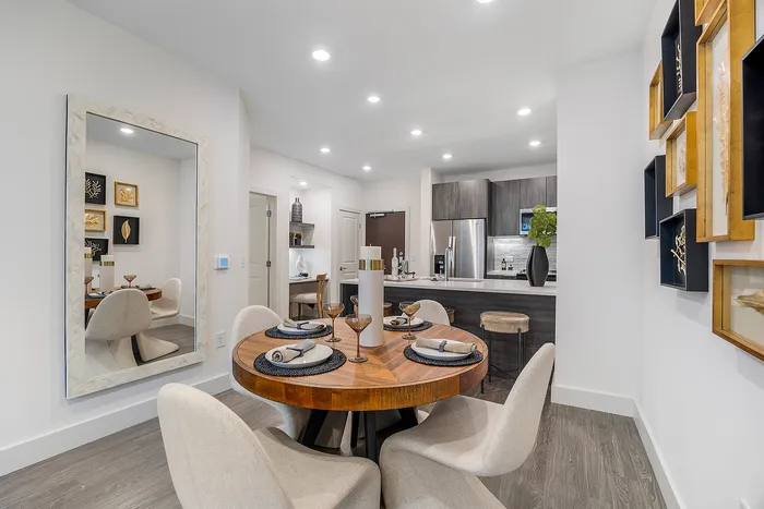 Contemporary dining and kitchen area with elegant decor, featuring a wooden round table set for four and a modern kitchen with stainless steel appliances.