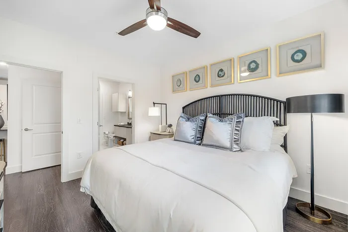 Elegant bedroom with sleek modern design, featuring a stylish bed with plush pillows, contemporary ceiling fan, and chic wall art, offering ultimate comfort and sophistication.