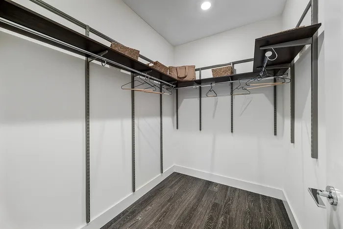 Spacious walk-in closet with sleek dark shelving, modern clothing hangers, and stylish storage baskets.