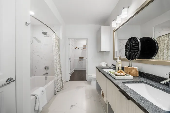 Elegant bathroom with marble tiles, stylish vanity, and walk-in closet access offering modern luxury.