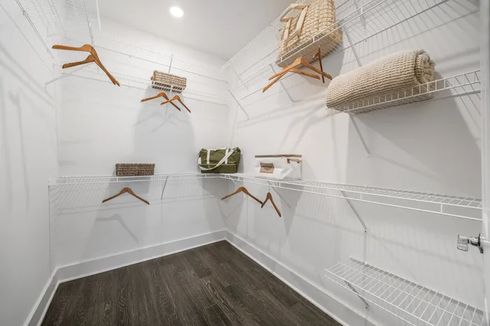 Spacious walk-in closet with sleek wire shelving, wooden hangers, and stylish storage baskets, offering ample organization space.