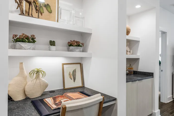 Chic home office nook with elegant decor, featuring modern shelving, lush greenery, and sophisticated artwork.