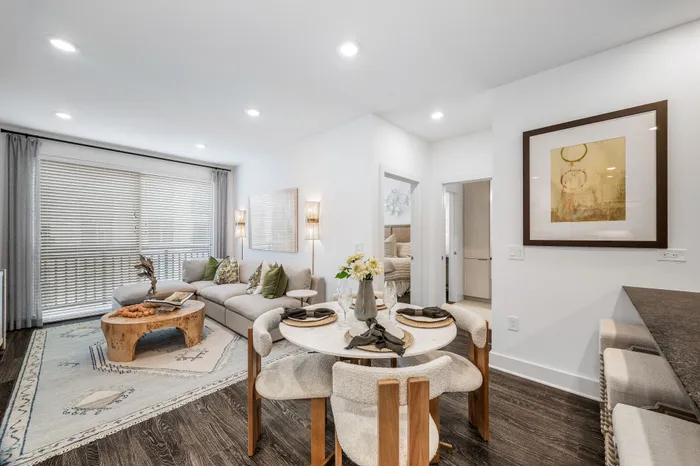 Modern open-concept living and dining area with cozy seating, elegant decor, and natural light streaming through large windows.