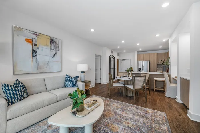 Inviting open-plan living area with a modern kitchen, elegant dining set, and chic lounge featuring contemporary artwork and stylish decor.