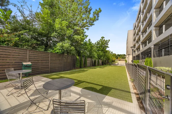 Charming outdoor area with modern patio seating, manicured lawn, and lush greenery, ideal for relaxation and social gatherings.
