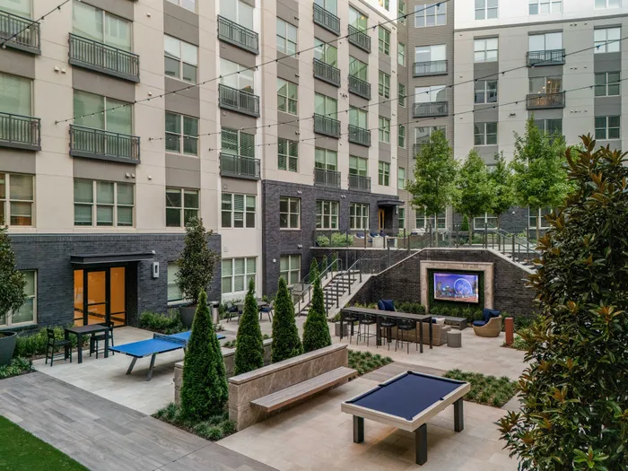 Modern apartment courtyard featuring lush greenery, outdoor seating, and recreational areas with a sleek urban design.