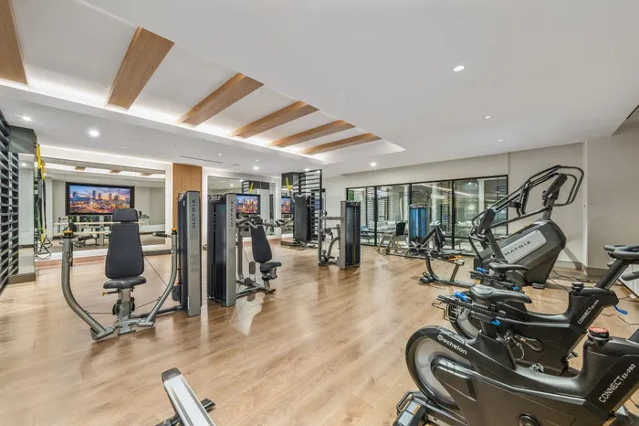 Modern gym facility with state-of-the-art exercise equipment, inviting wooden floors, and sleek design ideal for fitness enthusiasts.