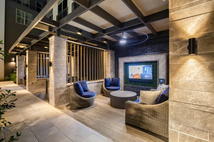 Luxurious outdoor lounge with modern wicker seating, ambient lighting, and a built-in entertainment screen.