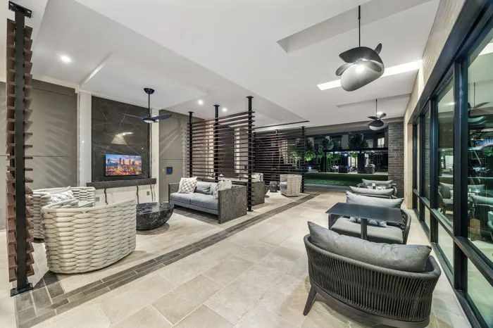 Luxurious open-air lounge area featuring modern seating, stylish ceiling fans, and a beautiful view of landscaped gardens.