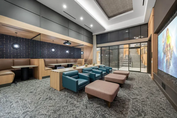 Modern communal lounge featuring plush seating, stylish decor, and a large projection screen, perfect for social gatherings.