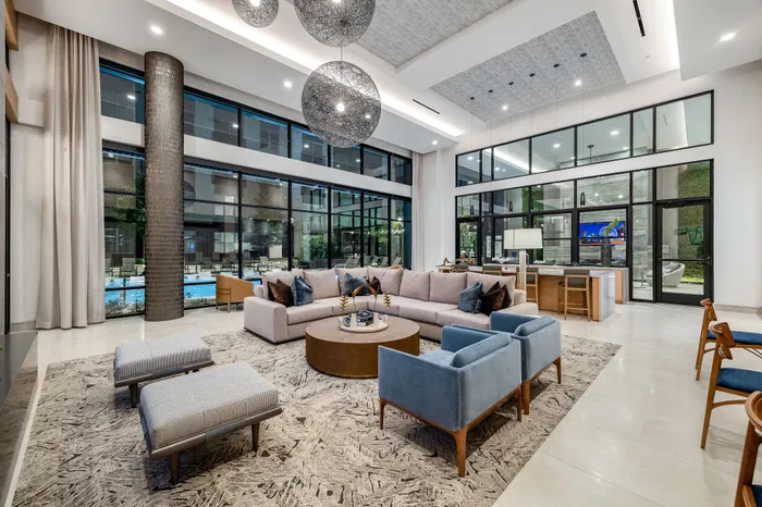 Luxurious modern lounge with a spacious open layout, featuring stylish seating, large windows, and elegant lighting fixtures that create a warm and inviting atmosphere.