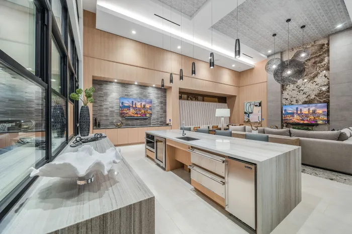 Luxurious open-concept living area featuring a modern kitchen island, elegant lighting, and cozy seating, perfect for entertaining.
