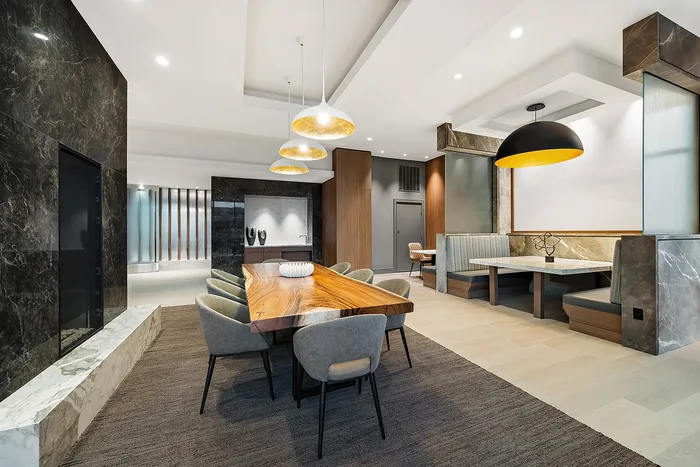 Modern dining and lounge area with sleek wood and marble accents, featuring stylish pendant lighting and comfortable seating.