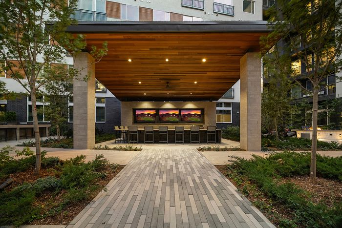 Chic outdoor lounge with a modern wooden pergola, sleek bar seating, and elegant landscape design, perfect for entertaining.