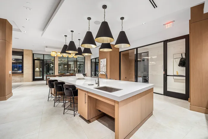 Luxurious modern kitchen with sleek lighting, spacious island, and elegant seating, perfect for entertaining.